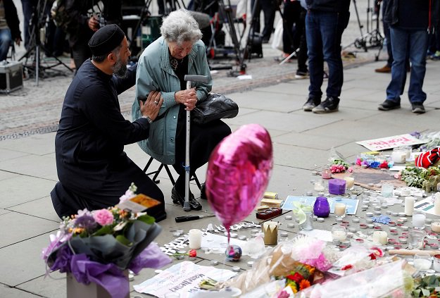 A Jewish woman named Renee Rachel Black and a Muslim man named Sadiq Patel react next to floral tributes in St Ann’s Square in Manchester, Britain. PHOTO: REUTERS