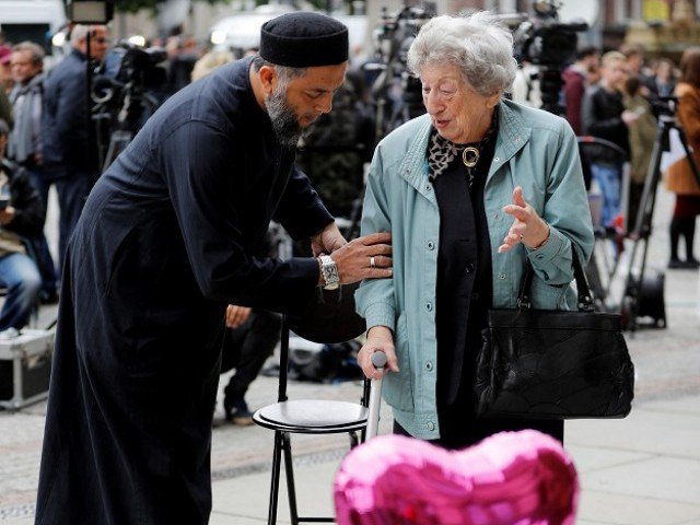 A Muslim man named Sadiq Patel comforts a Jewish woman named Renee Rachel Black next to floral tributes in Albert Square in Manchester, Britain. PHOTO: REUTERS